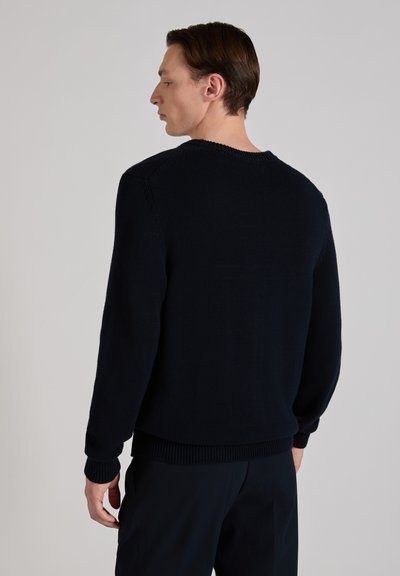 Suéter de punto azul marino con cuello redondo, mangas largas, puños y dobladillo acanalados. Tejido texturizado visible desde la vista posterior.
