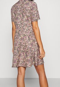 Robe à manches courtes fleurie en rose clair, dotée d'un motif multicolore de petites fleurs sur un fond sombre. Design à jupe évasée.