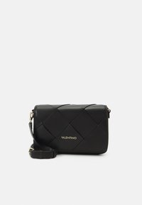 Borsa a tracolla nera in pelle con design trapuntato, logo dorato, tracolla regolabile e forma rettangolare. Presenta una texture liscia e uno stile minimalista.