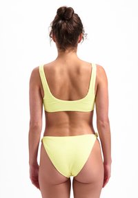 Žlutý texturovaný bikinový plavky s crop topem a vysokým pasem. Disponují širokými ramínky a bezproblémovým designem s minimálním použitím kovových komponentů.