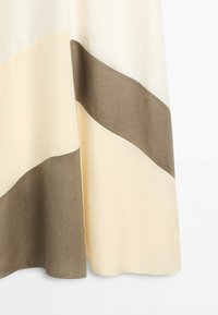 Close-up of fabric with wide horizontal beige and light brown stripes, showing texture and soft folds.
