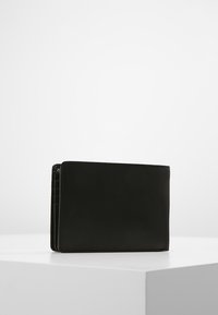 Čierna kožená peňaženka, obdĺžnikový tvar, hladká textura, minimalistic design, s viacerými priehradkami na karty a jemne embosovaným vzorom.