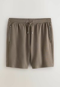Lysebrune atletikshorts lavet af et blødt materiale. Har en elastisk talje med snøre og to lynlåslommer på siden.