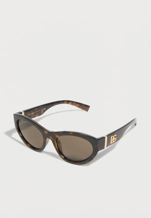 Γυαλιά ηλίου με σκελετό καφέ-μπεζ χρώματος χελώνας σε σχήμα γάτας, με σκουρόχρωμους φακούς και χρυστό λογότυπο "DG" στα πλάγια, τοποθετημένα σε λευκό απλό φόντο.