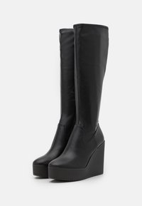 Black leather knee-high wedge boots with a smooth finish, rounded toe, and a thick, textured sole for added grip.