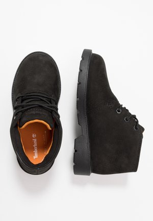 Czarne zamszowe botki za kostkę z czarną gumową podeszwą. Wyposażone w pomarańczowe wkładki i czarne sznurowadła. Okrągły nosek z dwoma oczkami na sznurowadła.