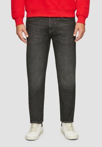 Jeans gris foncé avec une coupe droite, cinq poches et une légère décoloration. Portés avec un sweat-shirt rouge et des baskets blanches.
