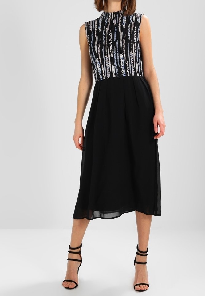 Robe sans manches avec un haut à motif bleu et noir à rayures verticales, se prolongeant en une jupe noire unie à mi-mollet.