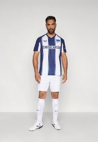 Blue and white striped soccer jersey with short sleeves, featuring a sponsor logo. Paired with white shorts and socks, and black cleats.