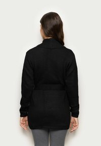 Czarny dzianinowy kardigan z kołnierzem szalowym, z pasem w talii, długimi rękawami i prążkowaną teksturą. Zaprojektowany w luźnym fasonie.