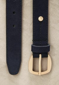 Cintura in suede blu navy con fibbia in metallo dorato, cinque fori per la regolazione e cuciture rinforzate lungo i bordi.