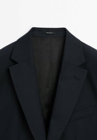 Marineblauer Blazer mit Nadelstreifen, mit Spitzenrevers, einer einzelnen Tasche und glatter Innenauskleidung. Enthält ein Etikett mit der Aufschrift "Made in Portugal."