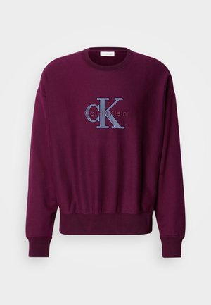 Bordo dukserica s dugim rukavima, rebrastim manžetama i rubom. Sadrži plavi izvezeni Calvin Klein logo na prsima. Mekana tekstura tkanine.