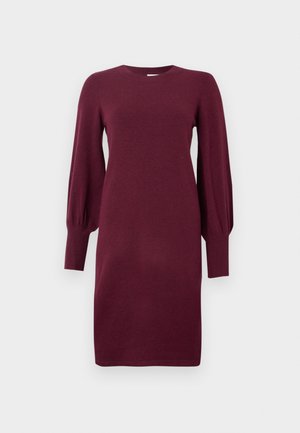 Robe tricotée bordeaux avec un col rond, des manches bouffantes longues et des poignets côtelés. Texture lisse, longueur genoux et silhouette ajustée.