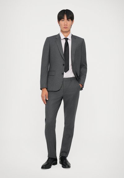 Traje gris con un diseño ajustado, blazer de un solo botón, dos botones, pantalones de pierna recta, combinado con una camisa rosa claro y una corbata negra.