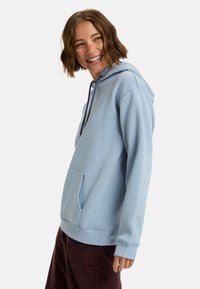 Sudadera de color azul claro hecha de una tela suave, con un bolsillo canguro, capucha con cordón ajustable y puños acanalados. Textura lisa.