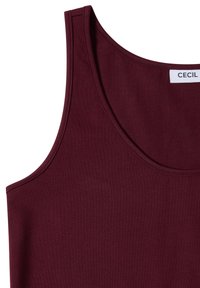Débardeur bordeaux sans manches avec encolure ronde et bords cousus, montrant partiellement l'étiquette de marque "CECIL" sur une étiquette blanche.