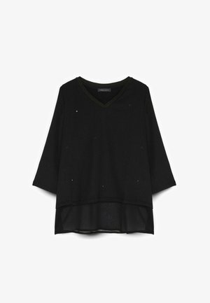 Blusa negra de manga larga con escote en V, pequeños tachones decorativos y detalle de dobladillo transparente en capas.