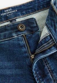 Slim-fit spijkerbroek in donkerblauw, met contrasterende stiksels, een metalen knoopsluiting en een zichtbare rits met een gestreepte voering.
