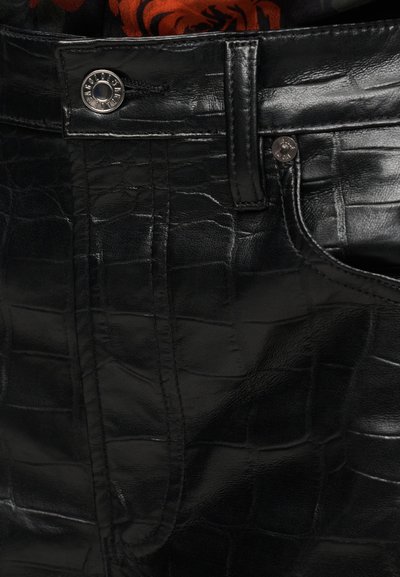 Μαύρο παντελόνι από δερματίνη με υφή που μοιάζει με κροκόδειλο, με μεταλλικό κουμπί και ενισχυμένη ραφή κα τά μήκος των ραφών.