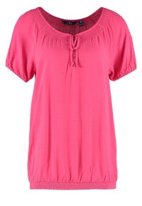 Chemise rose à manches courtes avec un col rond, des détails smockés et une fermeture nouée au cou. Tissu doux avec une coupe décontractée et un ourlet élastique.