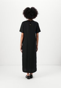 Black, knee-length dress with short sleeves, a straight cut, and a back fastening detail. Made from lightweight fabric, minimalistic design.