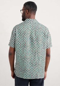 Camisa de manga corta hecha de una tela ligera que presenta un patrón de tablero de ajedrez en verde, blanco y marrón, con un corte relajado y cuello doblado.