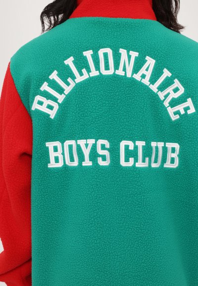 Czerwona i turkusowa polarowa kurtka z białym haftowanym napisem "BILLIONAIRE BOYS CLUB" na plecach, zaokrąglony fason, miękka tekstura.