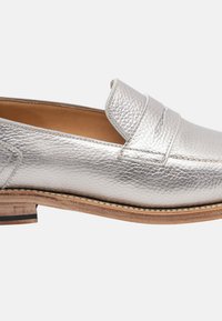 Mocassino in pelle metallizzata argento con finitura testurizzata, dotato di un tacco in legno basso e impunture lungo la suola.