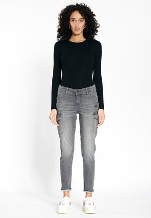 Graue Cargo-Jeans mit Fronttaschen und schmalem Schnitt, kombiniert mit einem eng anliegenden schwarzen Langarmshirt und weißen Sneakern. Einfaches Design, lässiger Stil.