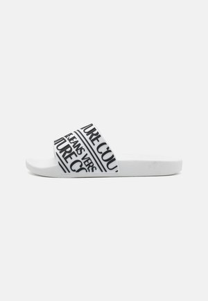 White slide sandal with a wide strap featuring black text patterns. Text includes "FUTURE" and "JEANS." Textured sole for grip.
