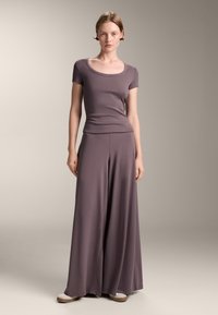 Top scurt cu maneci, dintr-un material ribbed de culoare mov, asortat cu pantaloni largi și fluidi. Țesătură moale, ușoară, cu o textură netedă. Design casual.