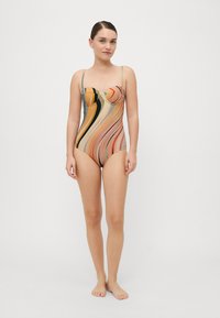 Egyrészes bikini, amely multiszínű, hullámos csíkokkal rendelkezik barack, sárga és fekete árnyalatokban. Vékony, állítható pántokkal és formázott mellrészsel rendelkezik.