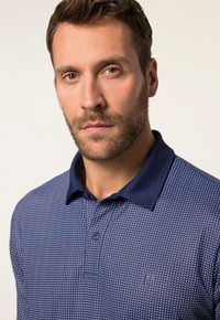 Námorní modré polo tričko s texturovaným vzorem, s dvoutlačítkovým zapínáním a kontrastním límečkem. Na hrudi má vyšívané logo.