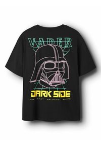 Musta lyhythihainen t-paita, jossa on kuva kypärästä vaaleanpunaisilla ääriviivoilla, vihreä ruudukko ja teksti "VADER DARK SIDE" keltaisella.