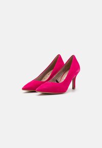 Escarpins en daim rose à talon haut avec un design à bout pointu et un talon fin. L'intérieur présente une texture lisse et des détails de marque minimalistes.