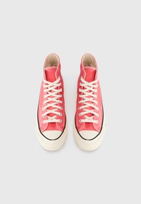 Υψηλά αθλητικά παπούτσια από κοραλλί καμβά με λευκά κορδόνια, καουτσούκ προφυλακτήρα στα δάχτυλα και μαύρες λεπτομέρειες. Διαθέτουν ραμμένες λεπτομέρειες κατά μήκος των ραφών.