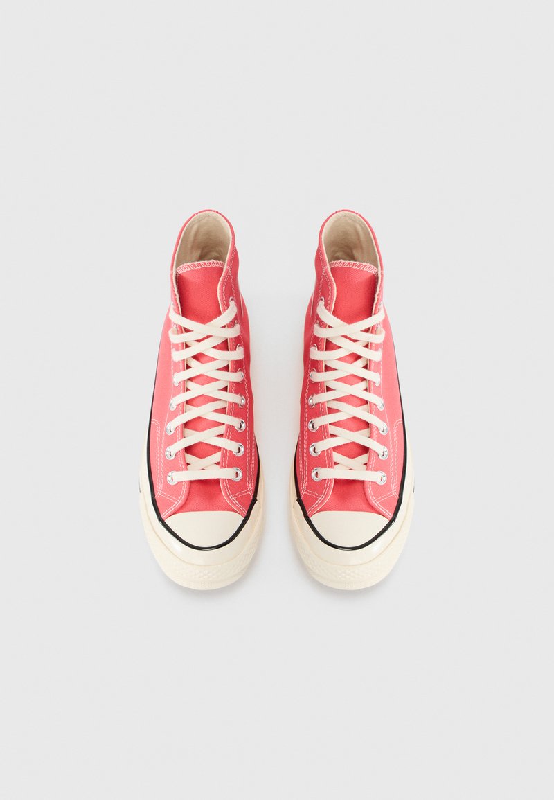 Høje sneakers i koralfarvet lærred med hvide snørebånd, gummitåhætte og sorte accenter. Har syning langs sømmene som detaljer.