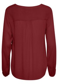 Haut à manches longues en tissu rouge profond. Présente un décolleté en U, un léger plissage au dos et des poignets boutonnés. Texture lisse sur toute la surface.