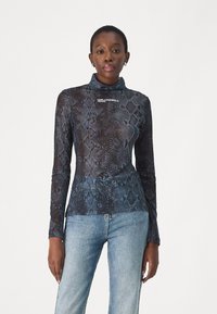 Langarmtop in donkerblauw met zwart slangenprint, gemaakt van doorschijnende stof, met een hoge kraag en een logo op de borst.