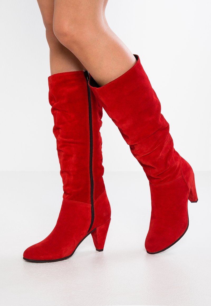 Bottes montantes en daim rouge avec un design décontracté, un bout pointu et un talon effilé. Dotées d'une fermeture éclair latérale.