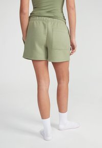 Groene katoenen shorts in een blend met een elastische tailleband, voorzien van een achterzak en een relaxte pasvorm. Draagt met witte geribbelde enkelkousen.