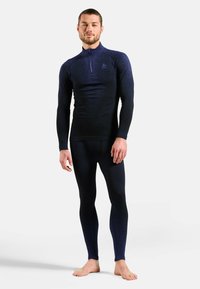 Navy long-sleeve top with a half-zip collar and textured fabric, paired with matching fitted leggings. Both pieces feature a sleek design.