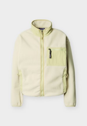 Helebeežist beež värvi täiszilindiline fliisjakk püstkraega, lukuga rinnatasku ja kahe küljetaskuga, millel on nööridega reguleeritavad avaused.