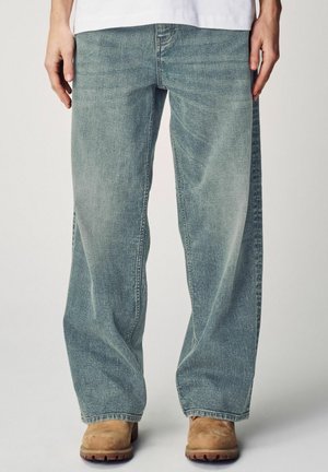 Lichtblauwe wijde jeans van denim, met een licht vervaagde structuur en een rechte snit, gestyled met een paar bruine klompen.