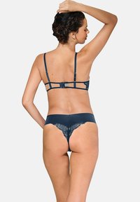 Ensemble de lingerie marine comprenant un soutien-gorge à dos en dentelle avec des bretelles réglables et un string avec un ourlet en dentelle festonnée, mettant en valeur un tissu lisse.