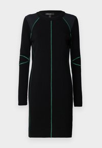 Schwarzes Strickkleid mit langen Ärmeln, das grüne Nähte entlang der Nähte und am Hals aufweist. Gerader Schnitt, runder Halsausschnitt und knielang.