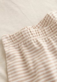 Gestreifter Stoff in sanftem Beige und Creme, mit einem elastischen Bund und gerafften Nähten, auf einer hellen Oberfläche platziert.