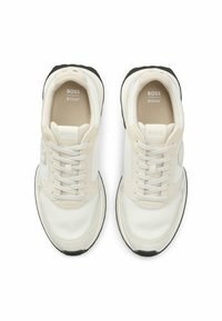 Sneakers bianchi e crema realizzati in mesh e materiali sintetici. Presentano un colletto imbottito, lacci, dettagli con logo e suola in gomma nera.