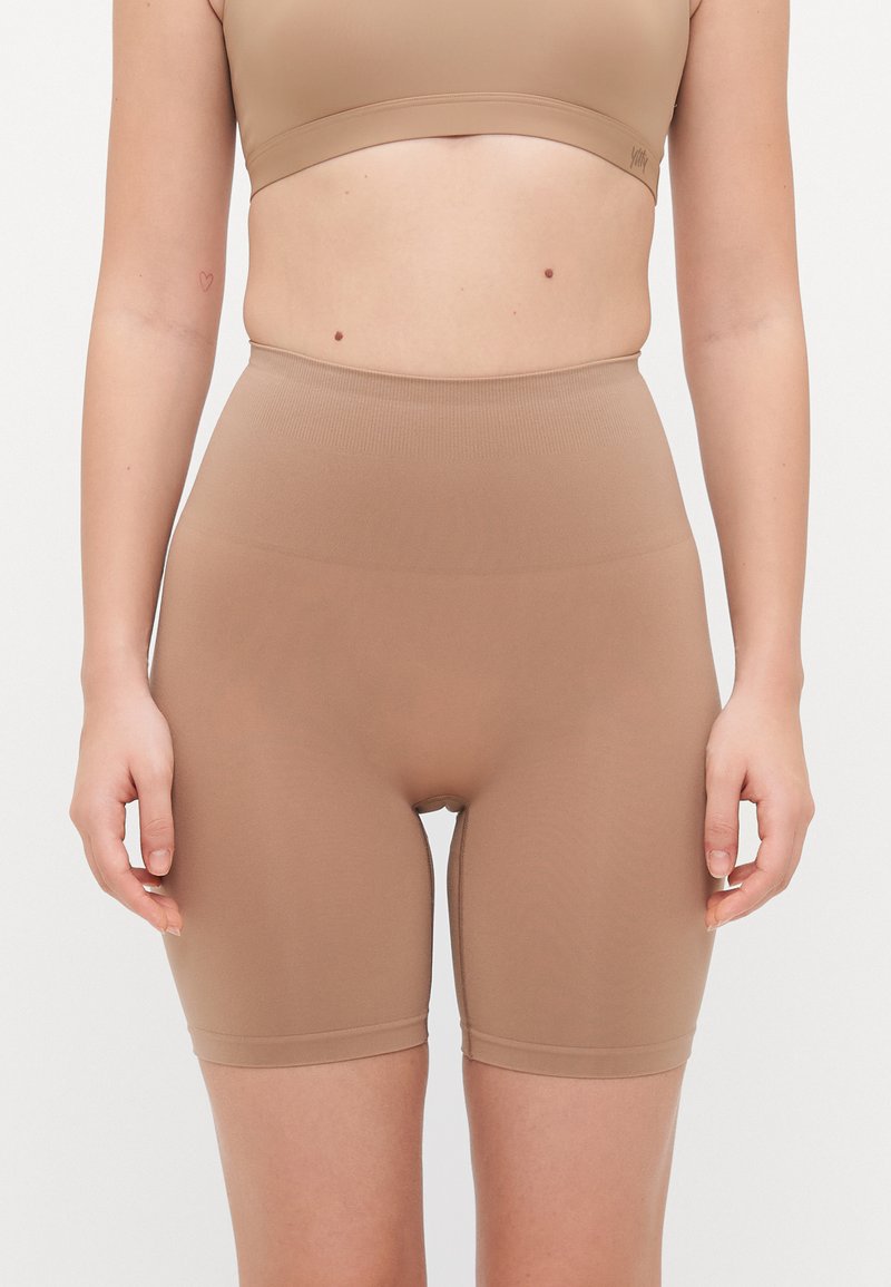 Bodysuit šortsevi u svijetlosmeđoj nijansi, izrađeni od rastezljivog materijala s visokim strukom, glatkom teksturom i uskim dizajnom.